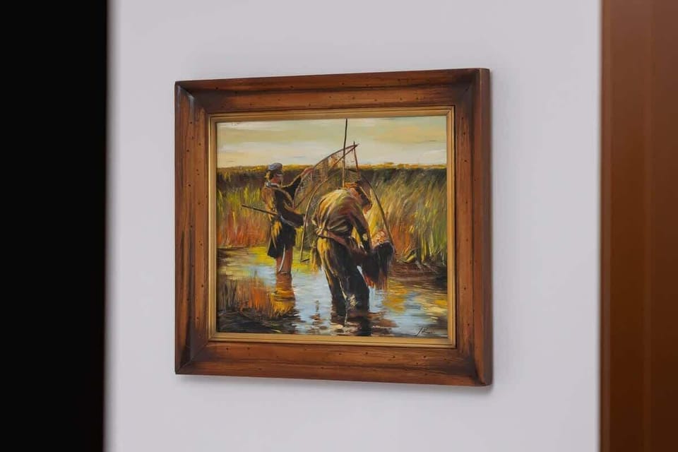 A framed painting with a rustic hunting scene, adding a classic and artistic element to the apartment’s decor.

