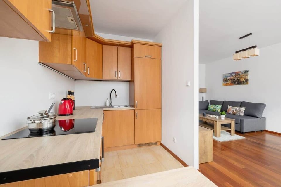 A compact and functional kitchen with wooden cabinetry, beige countertops, and modern appliances, seamlessly connecting to the living area.

