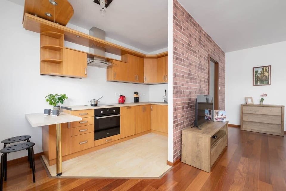 A different perspective of the kitchen, featuring an exposed brick wall, a built-in oven, and green plants for a fresh look.

