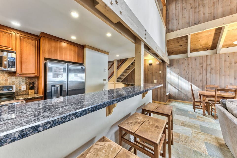 This gourmet kitchen features granite countertops, stainless steel appliances, and rustic exposed beams creating the perfect space for memorable meals.