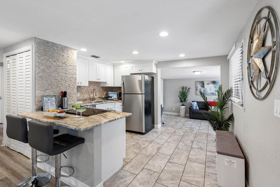 The modern appliances are all top-of-the-line, including a large refrigerator, a dishwasher, an oven with a built-in microwave, and a cooktop that is perfect for both everyday meals and elaborate dinners.