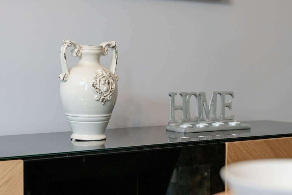 A decorative console table with an elegant ceramic vase and a "HOME" sign, adding a sophisticated touch to the interior.

