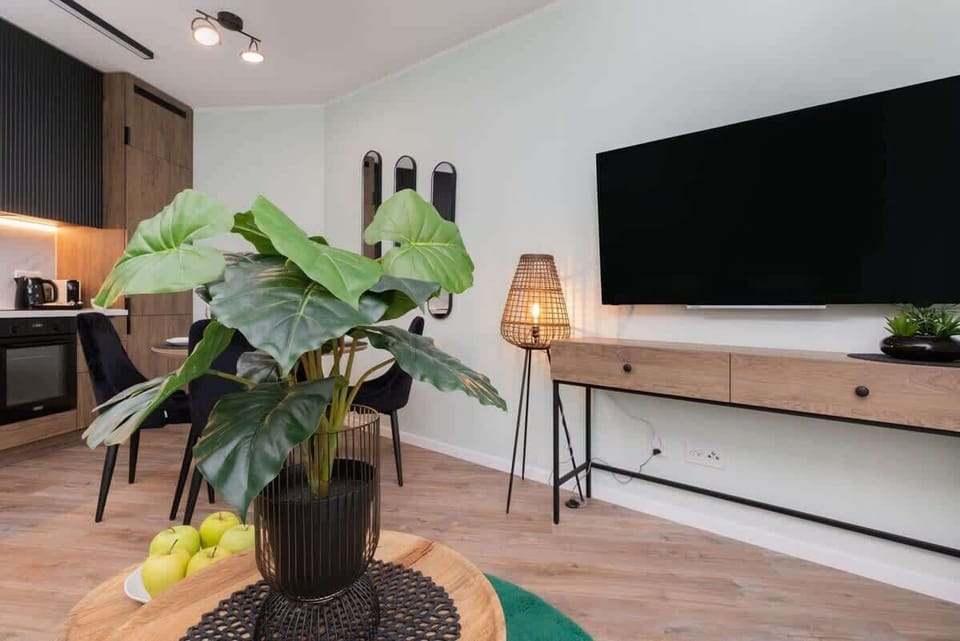 A modern entertainment area with a mounted TV, a wooden media console, and decorative elements enhancing the interior design.

