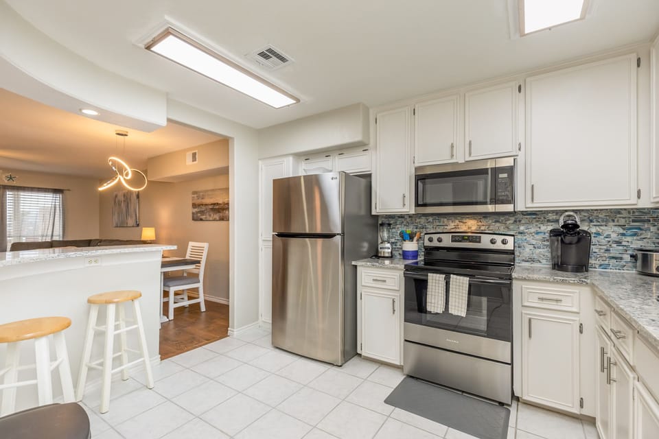Your bright, modern kitchen awaits with stainless steel appliances, granite counters, and stylish backsplash—perfect for whipping up morning coffee.