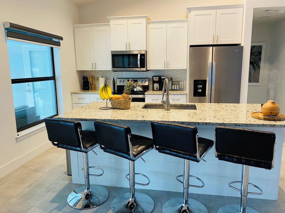 Kitchen counter with four bar stools with pool view