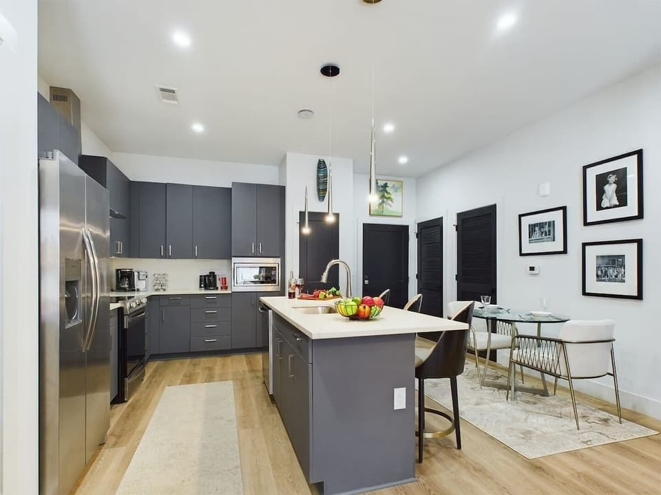 Fully equipped kitchen with stainless steel appliances, basic cooking essentials, toaster, coffee machine, kitchen island seating, and breakfast table for 2.