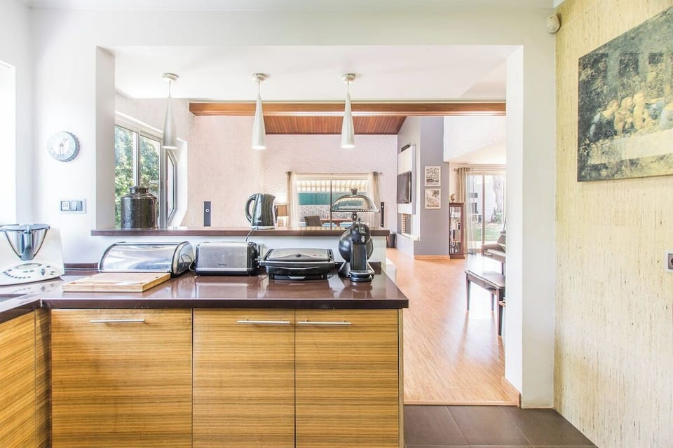Modern open-plan kitchen with wooden cabinetry and dark countertop — Villa Marina, holiday villa in Cascais