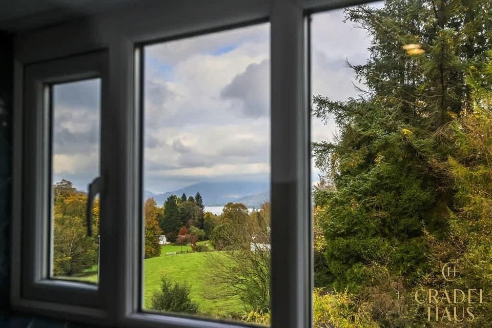 Take in the breathtaking views from Windermere's bathroom window, showcasing the scenic beauty of the Lake District, with Lake Windermere in the distance and lush greenery!