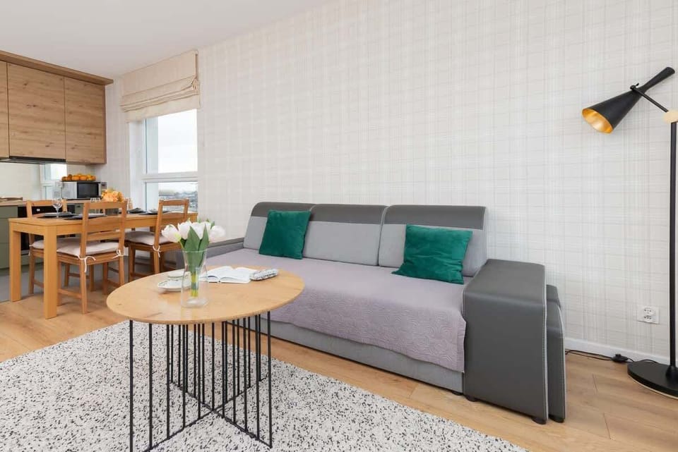 A spacious living and dining area with a neutral color scheme, a large window, and a stylish combination of furniture.

