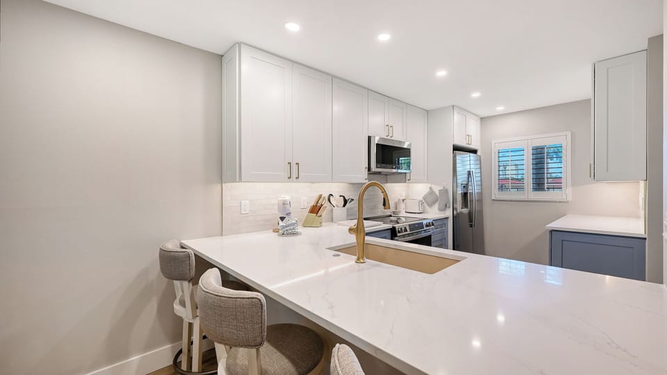 Prepare your favorite meals in this beautiful modern kitchen, featuring sleek white cabinetry, pristine quartz countertops, and stainless steel appliances. The spacious island doubles as a breakfast bar, perfect for morning coffee or casual dining.