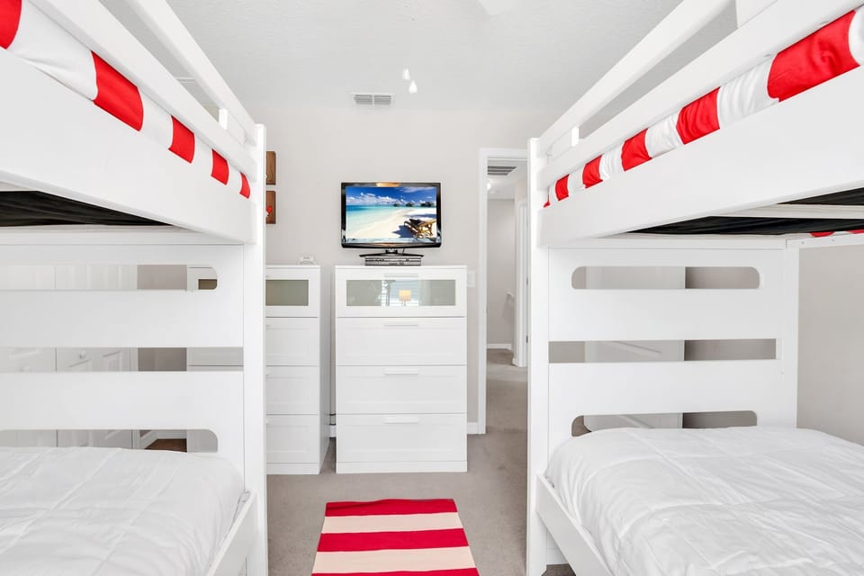 Another angle of the bunk room showcasing its bright, playful setup and TV.