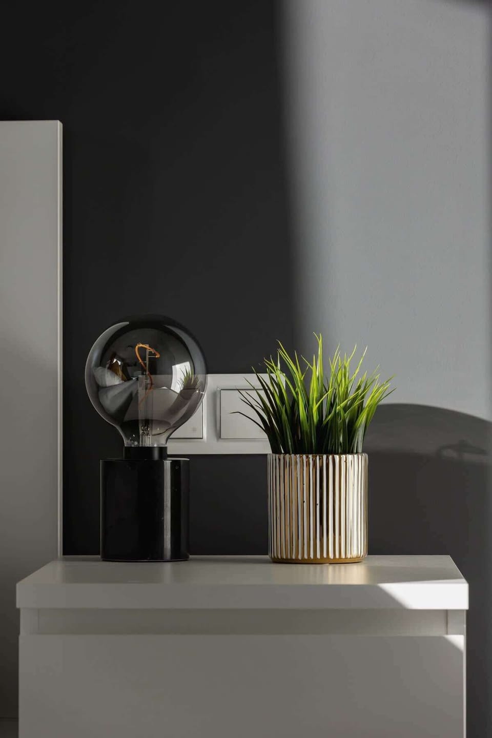 A decorative shelf with a green potted plant and a metallic ornament, enhancing the interior’s stylish and cozy feel.


