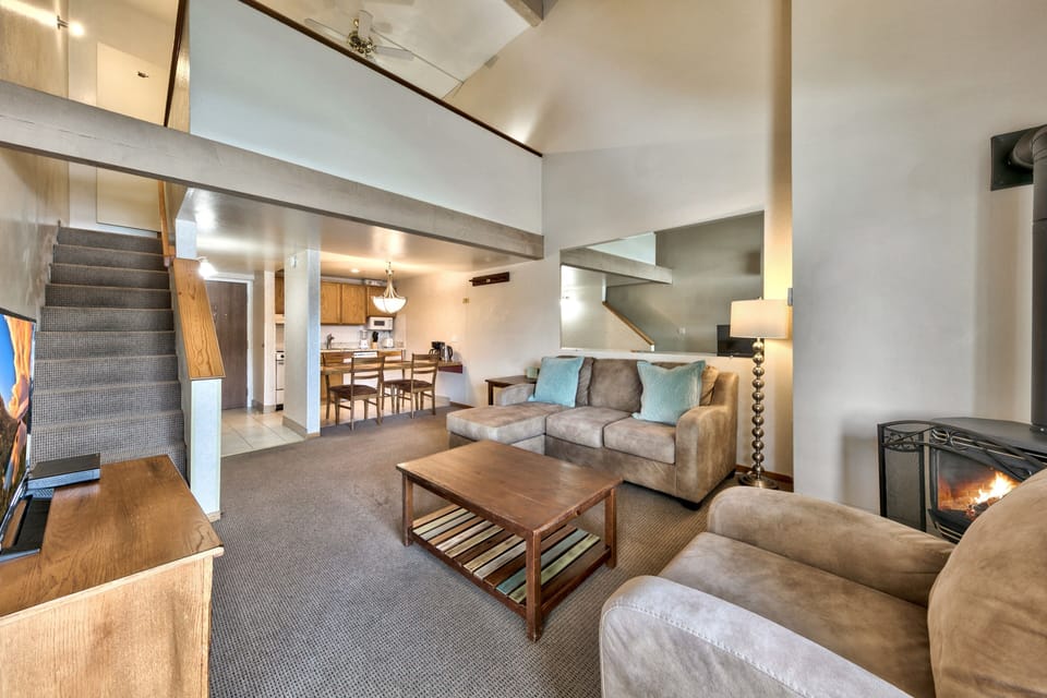 Relax in your spacious loft-style living area with soaring ceilings, cozy fireplace, and comfortable seating perfect for unwinding after mountain adventures.