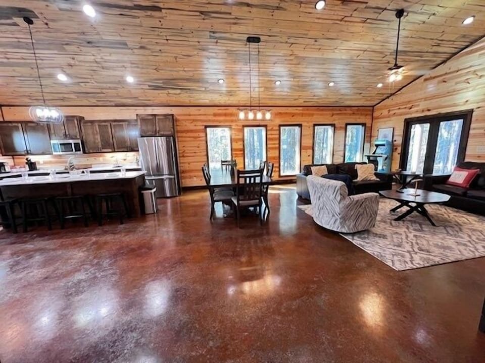 The open living room features vaulted ceilings and elegant modern design surrounded by peaceful forest views.