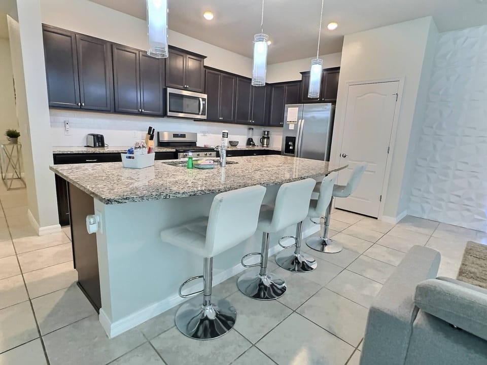 Enjoy this contemporary kitchen with sleek dark cabinetry and a beautiful granite island, ideal for casual dining. The modern pendant lighting enhances the space, creating a welcoming environment for collaboration and creativity.