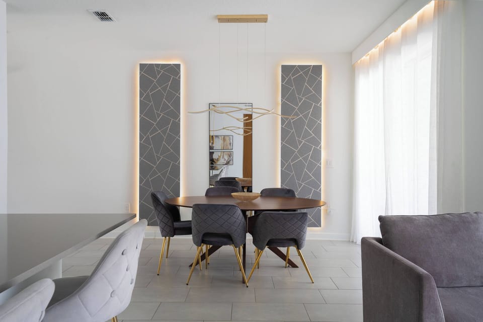 This bright dining area boasts a sleek wooden table and stylish gray chairs with gold accents, beautifully enhancing the elegant decor. Its minimalist design is perfect for both intimate dinners and lively gatherings.