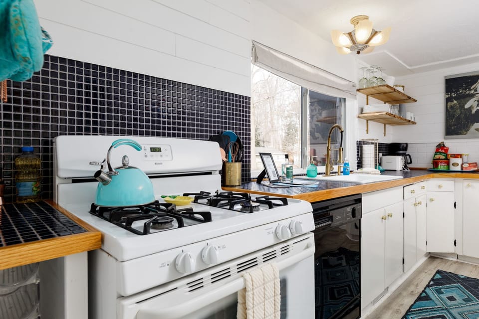 Classic stove set against a dark tile backsplash w/ open shelves for easy access to essentials.