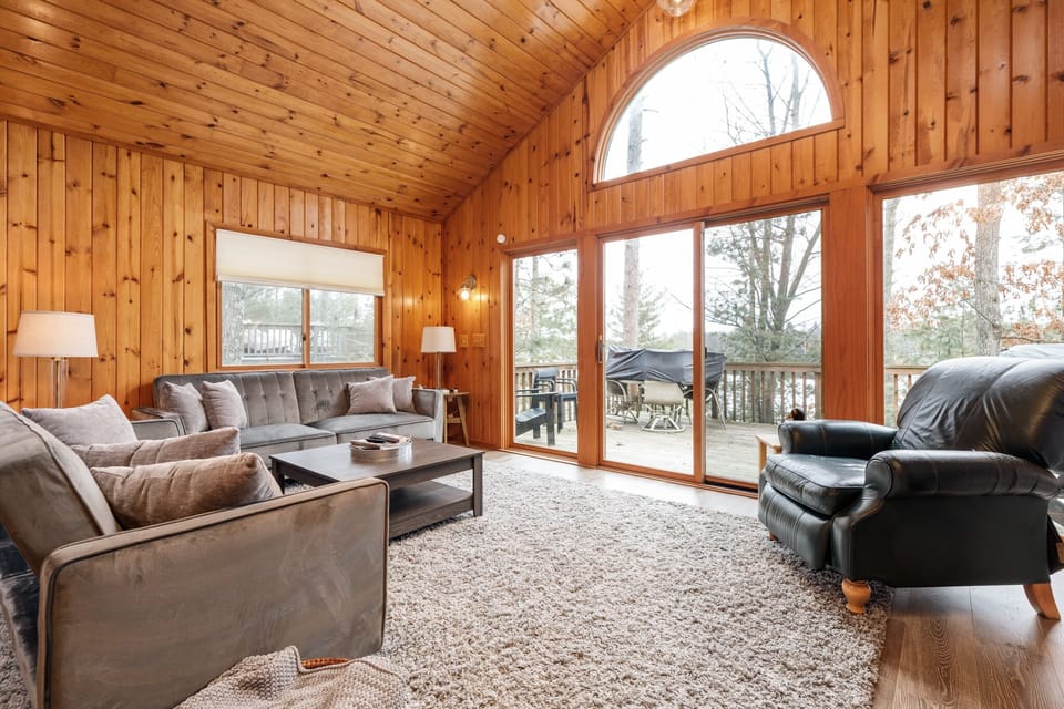 Bright living room w/ vaulted wood ceilings, plush seating & large arched windows overlooking the lake.