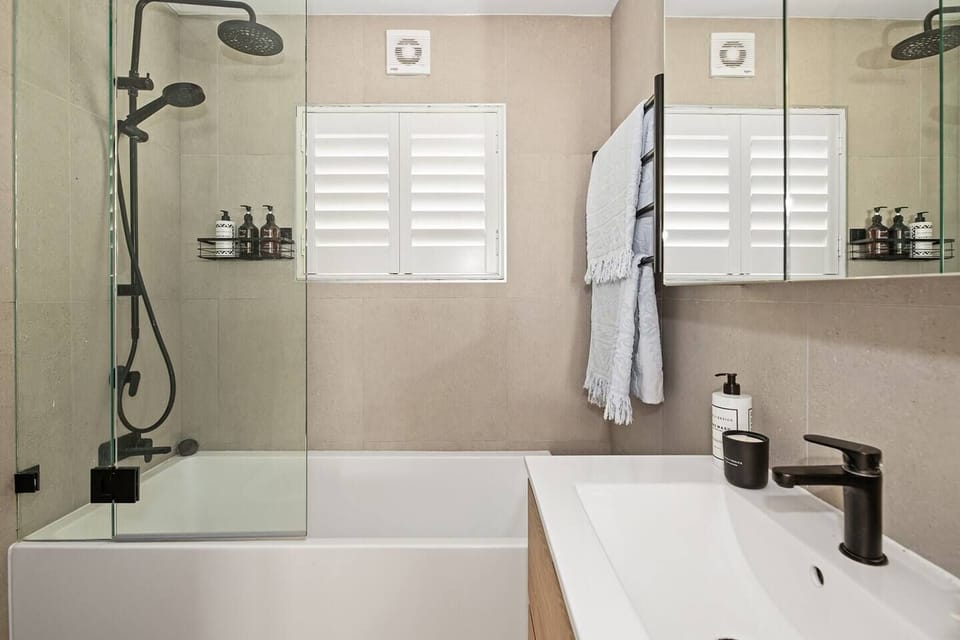 The stylish, contemporary bathroom features an overhead shower and a bathtub as well as complimentary toiletries. 
