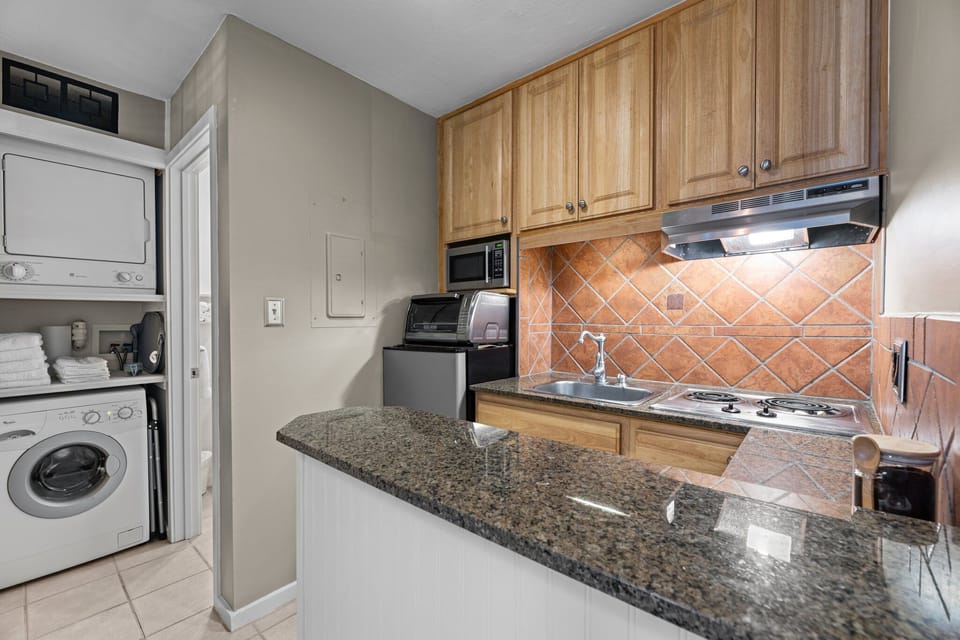 Efficient living: fully equipped kitchenette meets stacked laundry convenience.