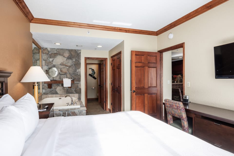 - Bedroom suite with king bed and in room stone accented jetted tub  
- Cozy atmosphere with flat screen TV and workspace for added comfort  
- Direct access to bathroom and living areas for easy convenience