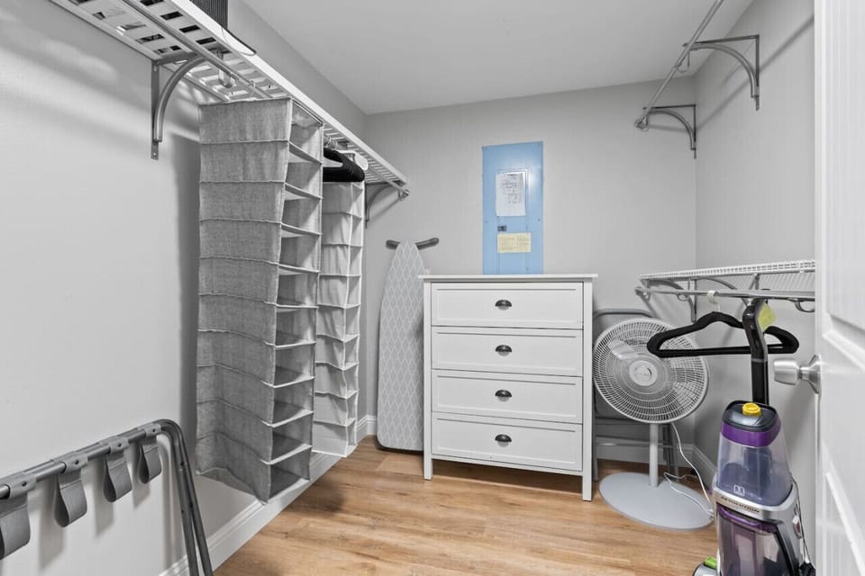 Primary bedroom`s walk-in closet with dresser and fan.