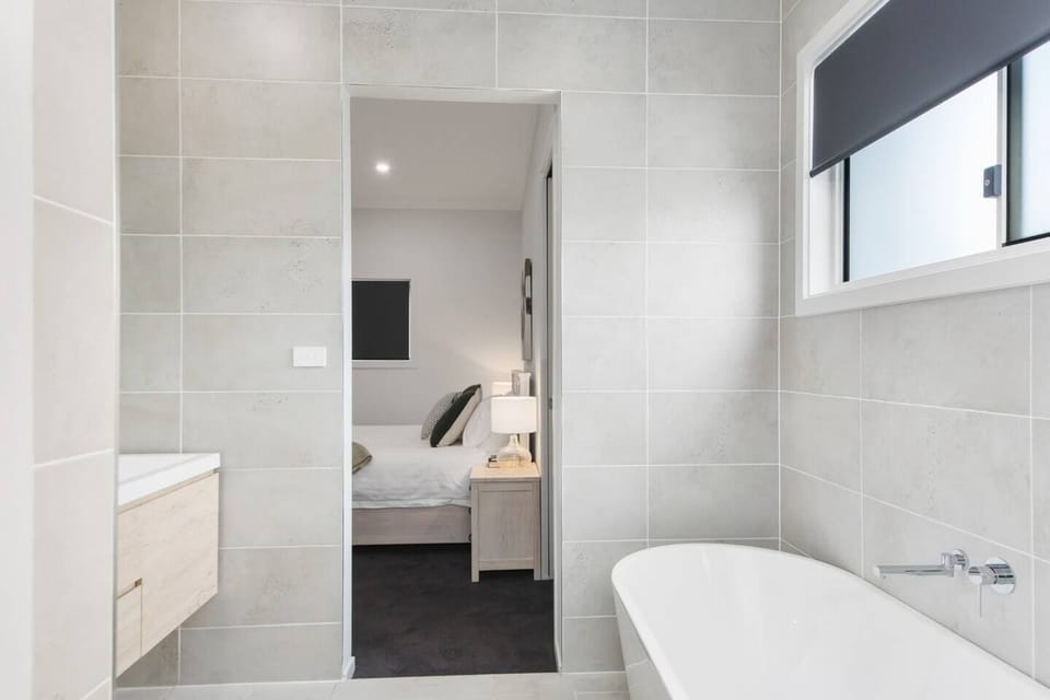 The primary bedroom boasts access to a modern ensuite bathroom, featuring a bathtub, shower and double vanity.
