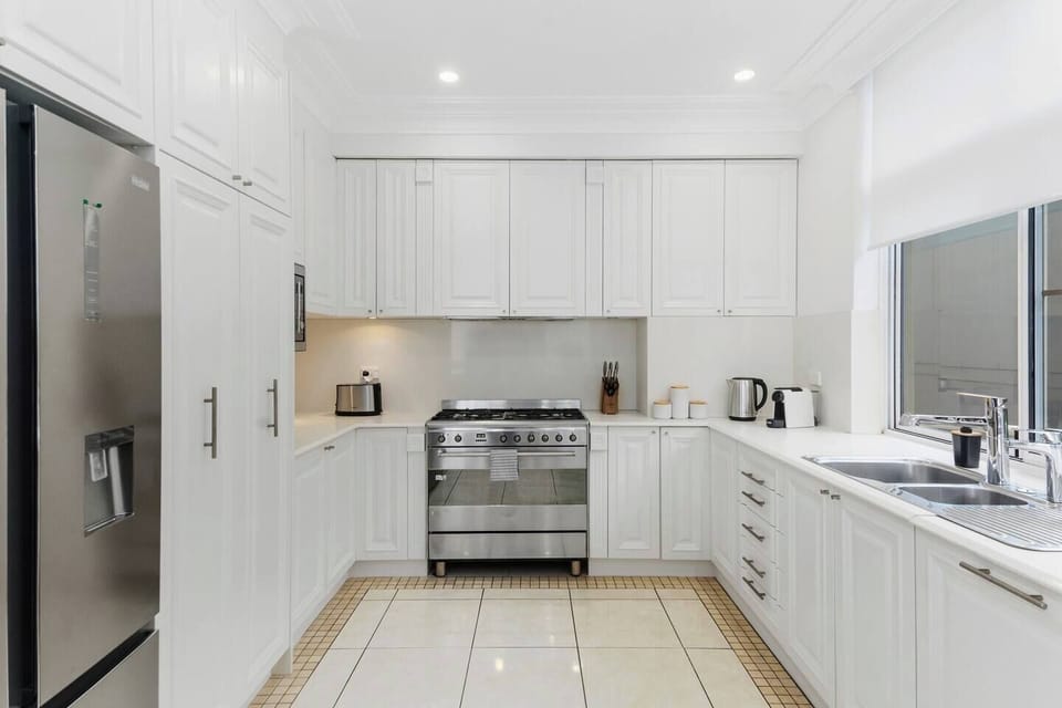 The kitchen boasts generous space with a sweeping wrap-around countertop, extra large oven and classic panelled cabinets providing ample storage.
