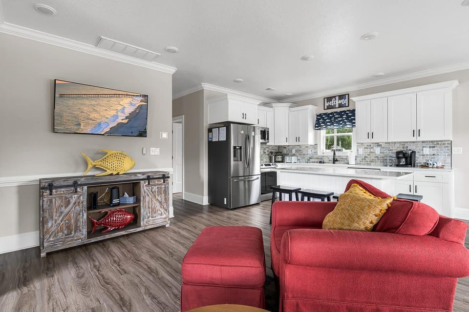 Bright, open kitchen and living area with cozy red sofa
