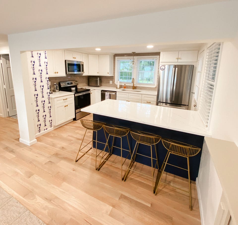 stunning kitchen with quartz counters, two tone cabinetry, and stainless appl.
