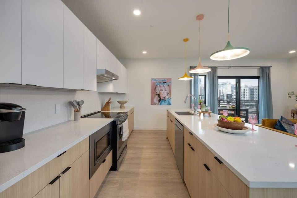 Fully equipped kitchen stocked with all culinary essentials and featuring brand-new stainless-steel appliances and a large kitchen island offering bar seating.