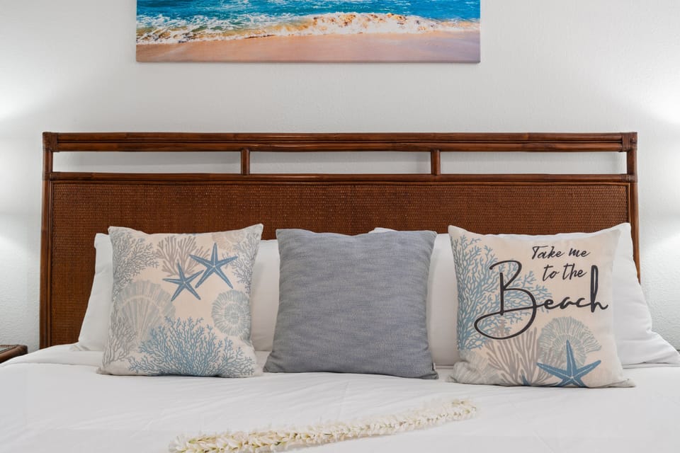 Coastal bedroom detail with decorative pillows and woven headboard.