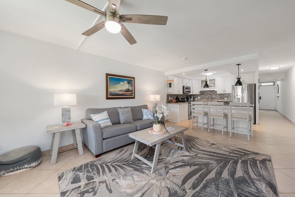 Spacious living room with sofa, coffee table, and bright coastal decor.
