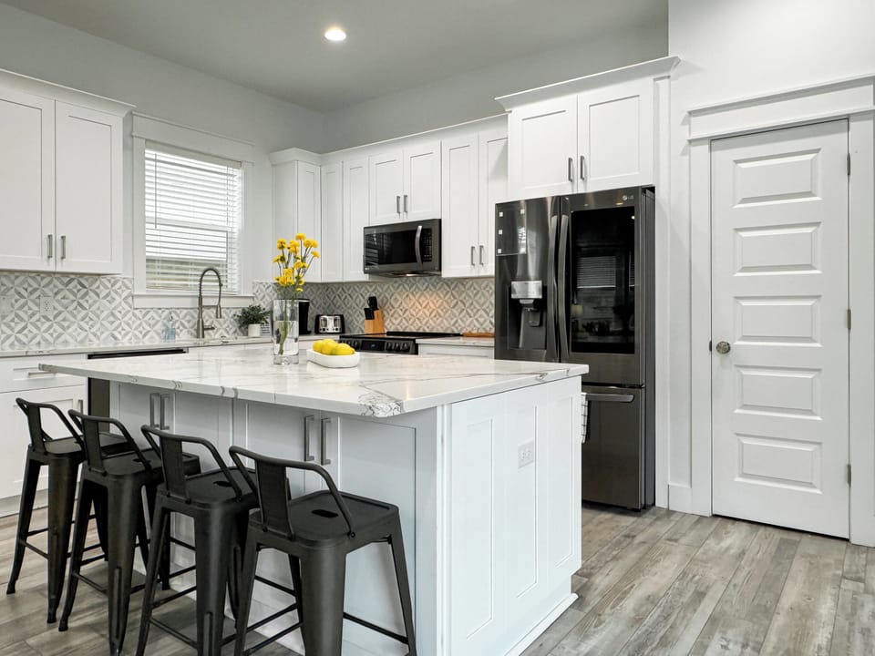 Sleek, modern kitchen featuring crisp white cabinetry, stainless steel appliances, and a spacious pantry.