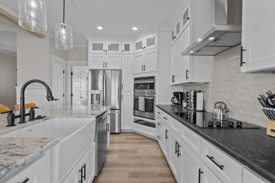 Top Level: Fully Equipped Kitchen with Refrigerator, Ovens, Electric Cooktop, Dishwasher, Sink, Coffee Maker, Toaster, and Essential Cooking Appliances