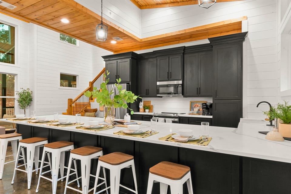The kitchen area combines sleek black cabinetry with a long white countertop, providing ample space for meal preparation and casual dining at the bar-style seating.
