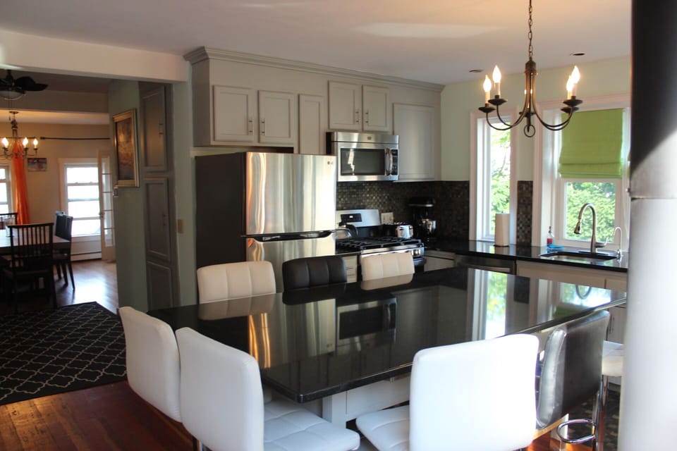Kitchen w/ss appliances, ots of cookware, dishes, and a large island w/ seating.