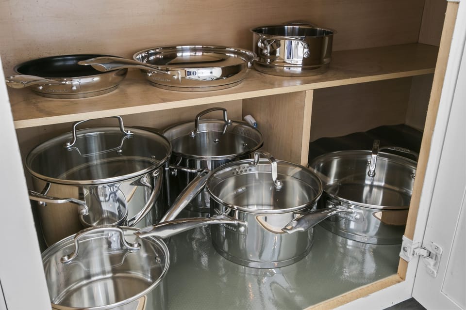 Base cabinet gleams with a collection of stainless steel pots and pans.