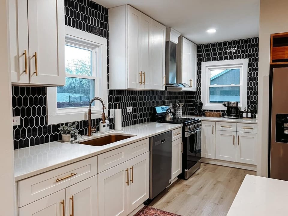 Bright kitchen w/ white cabinetry, tiled backsplash & stainless appliances for easy cooking