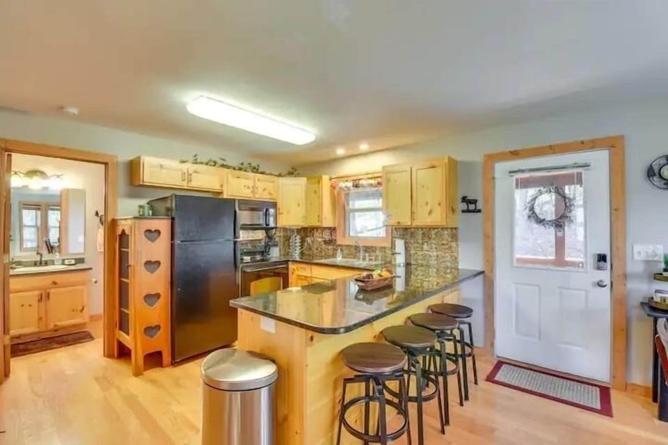 Bright kitchen featuring wood cabinetry, granite countertops, and bar seating for casual meals after a fun day of hiking.