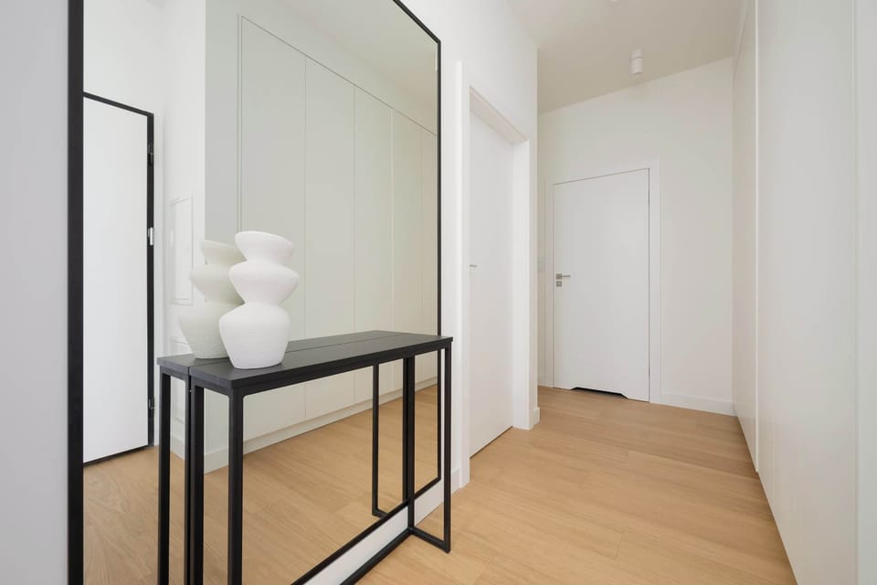 A bright hallway with a large mirror that gives the room a spacious feel and a modern look.