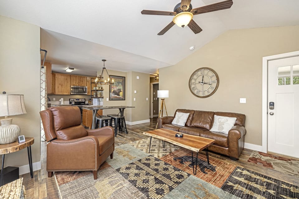Living area with a sofa, two chairs, flat screen TV and ceiling fan