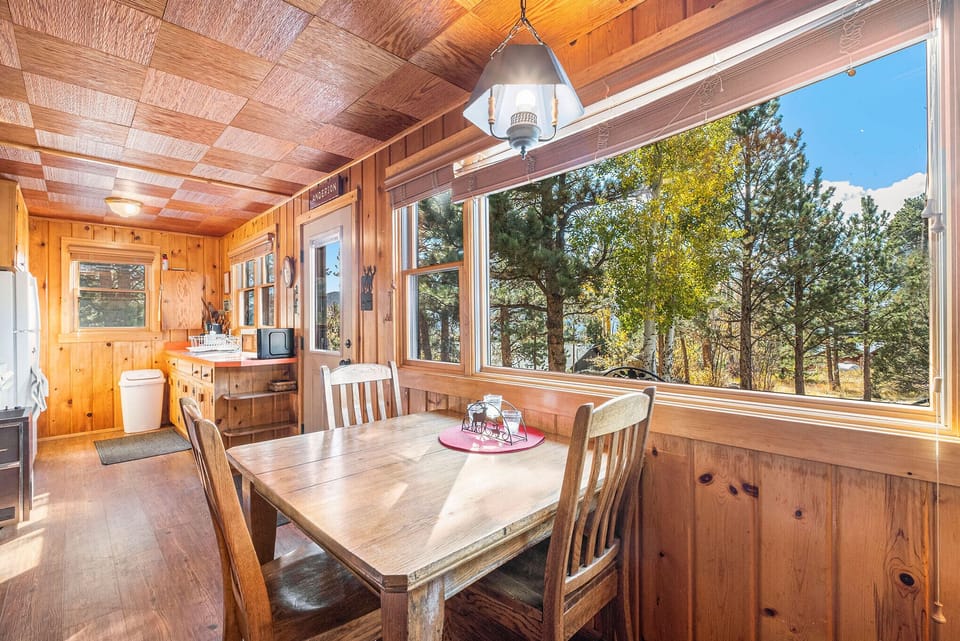 Chasm Cabin Estes Park, Dining table for three featuring a large window with beautiful mountain views.