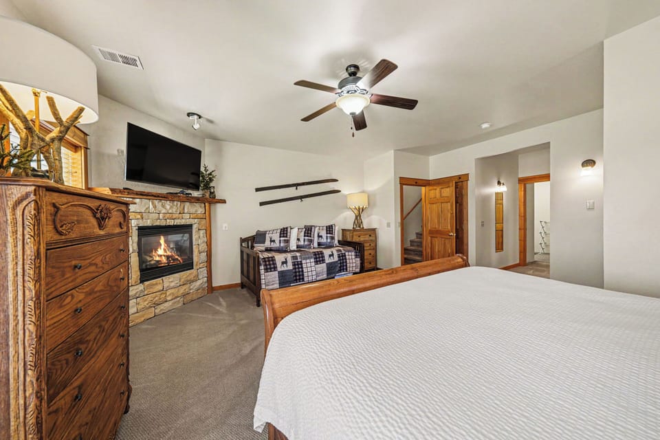 Unwind in your spacious retreat featuring a cozy fireplace, ceiling fan, and rustic wood accents that invite restful evenings after mountain adventures.