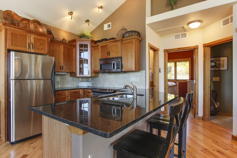Kitchen with breakfast bar and seating. Kitchen has full sized refrigerator, electric stove/oven and microwave. 