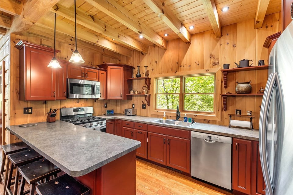 - Spacious cabin kitchen with modern stainless steel appliances   - Warm wood design and red cabinetry create cozy mountain charm   - Fully equipped cooking space for family meals and gatherings