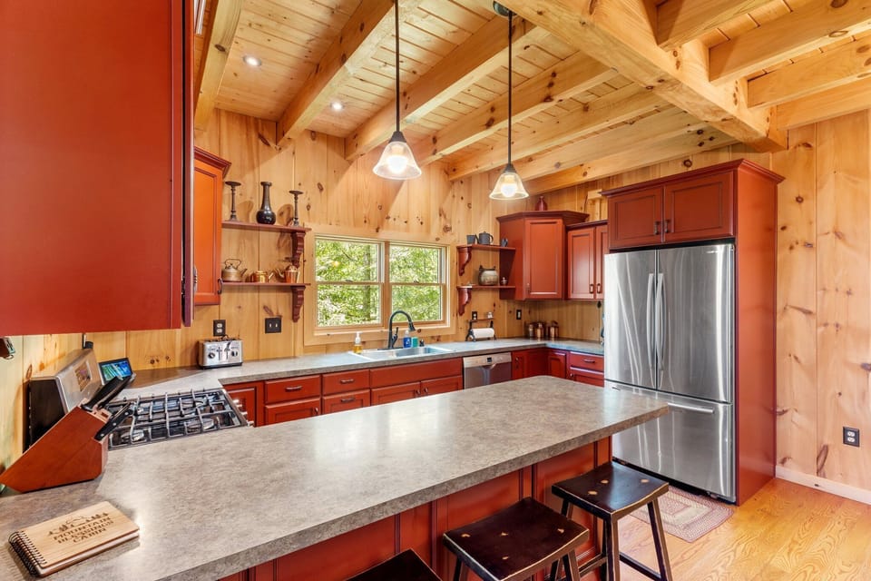- Spacious kitchen with stainless steel appliances and wood cabinets   - Fully equipped for family meals and cozy mountain dinners   - Natural light and open shelves create a warm cabin cooking space    2/2