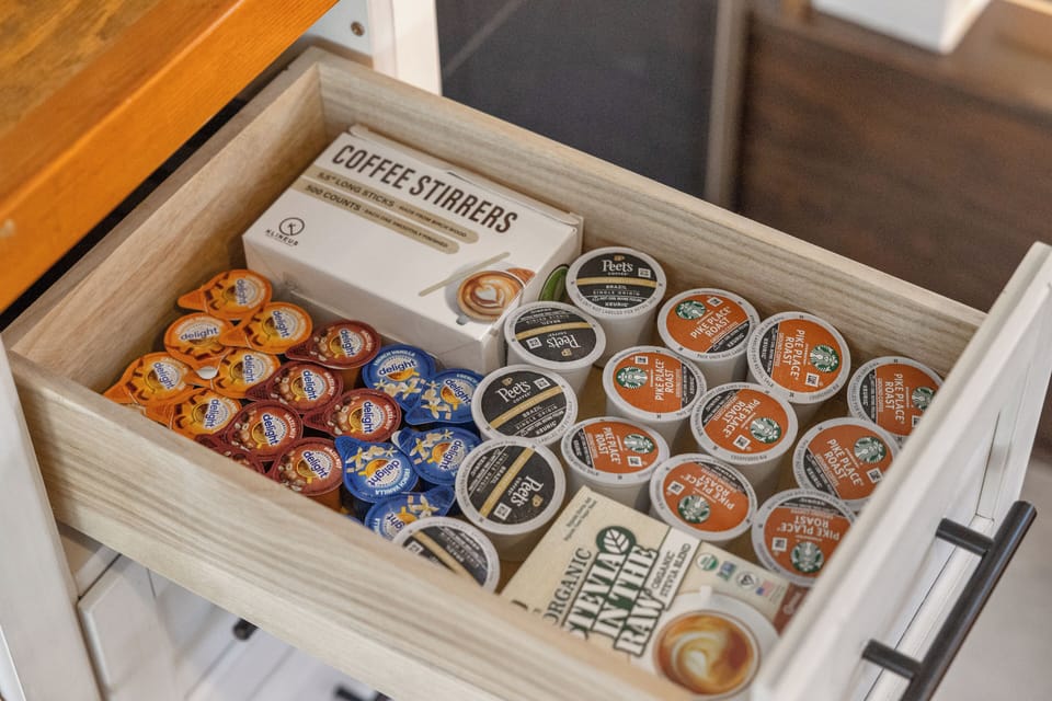 Loft kitchenette: coffee supplies drawer with pods, creamers, and stirrers.