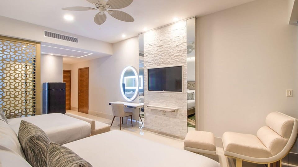 Stylish room with two beds, TV, and workspace at Garza Blanca Cabo.