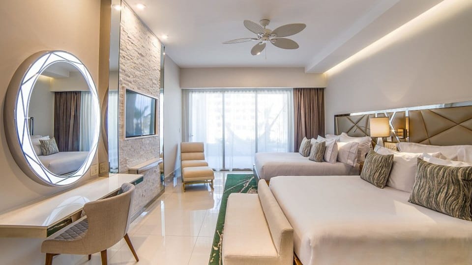 Elegant room with two beds, workspace, and balcony at Garza Blanca Cabo.